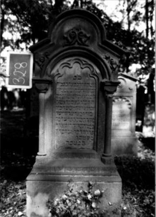 Grabstein 328 (Index: 100111962) Material: Sandstein Zustand: gut Maße HxBxT: 150x62x28 cm Beschreibung: ädikulaartige Stele mit 3/4-Säulen, profilierter Sockel, schräg eingezogener Rundbogenabschluß mit Verdachung, Schriftfeld eingetieft mit Rundbogenabschluß Symbolik: Ranken, Rundbogenfries: Grabstein 328