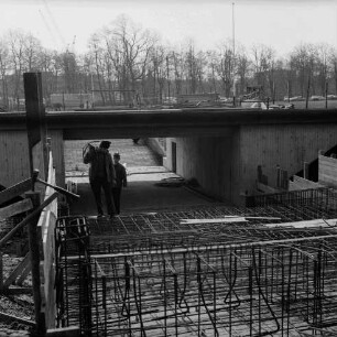 Konrad-Adenauer-Ring: Unterführung am Exer: Bauarbeiten: Blick auf Baustelle mit Holzverschalungen, Eisengittern und zwei Bauarbeitern: im Hintergrund Bäume, Baukräne und Gebäude