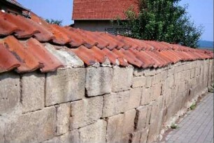 Mauer aus Sandsteinquadern mit Ziegeldach