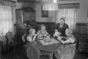Schleifer Frauen und Mädchen beim Kaffeetrinken nach dem Verzieren von Ostereiern. : Holcy a žony w Slepjanskej drasće po debjenju jutrownych jejkow při kófejpiću pola Wěrikec w Rownom.