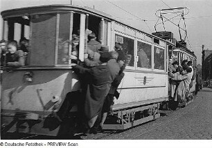 Dresden. Überfüllter Straßenbahnzug der Linie 11 nach Bühlau mit Fahrgästen an den offenen Einstiegen hängend
