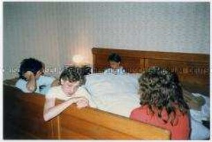 Jugendliche sitzen erschöpft auf einem Bett (Altersgruppe 14-17)