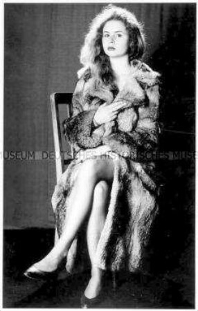 Junge Frau sitzt im Pelzmantel auf einem Stuhl (Prämiertes Foto Sonderthema: Kleider machen Leute)