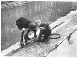 Jungen spielen im Regenwasser am Straßenrand