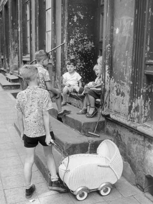 Hamburg-Altona. Im Wohnquartier Hexenberg. Spielende Kinder an einem Hauseingang. Ein Junge hat einen Puppenwagen an der Hand