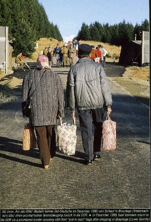 Ehepaar geht über einen geöffneten Grenzübergang bei Braunlage im Harz im Dezember 1989 zurück in den Osten, bepackt mit Einkäufen in Beuteln