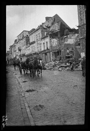 Bapaume (Dep. Pas-de-Calais, Frankreich): Pferdegespann auf einer gepflasterten Straße vor einer Häuserzeile mit einer Gebäuderuine (Distanzaufnahme) ("Straße während der Sommeschlacht")