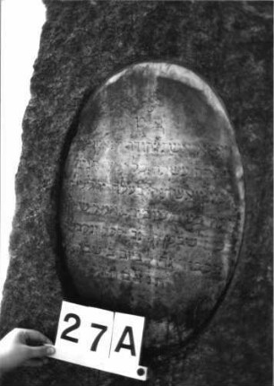 Grabstein 27 (Index: 100081749) Material: Granit, weiße Marmorplatte Zustand: verwittert Maße HxBxT: 146x56x30 cm Beschreibung: konische Stele, gerader Abschluß, ovale und querrechteckige Schriftplatte: Grabstein 27A