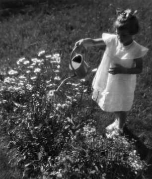 Kinderbilder. Kleines Mädchen beim Blumengießen in einem Garten