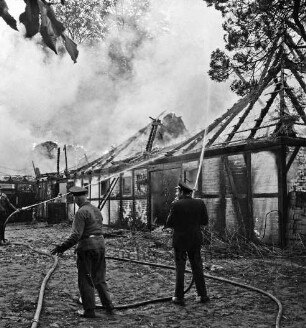 Schleushörn: Brand: Trabergestüt und Reitstall "Schleushörn" von Klaus Martens: brennender Stall mit Reetdach: darüber Rauchwolken: vorn und links Feuerwehrmänner beim Löschen