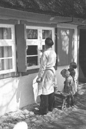 Althagen: Maler streicht Fenster, zwei Kinder dabei