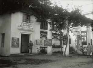 Der Fotograf Adolf Beckmann vor seinem Atelier am Ende der Kolonnaden, aus dem Fenster im Obergeschoss wohl seine Frau blickend