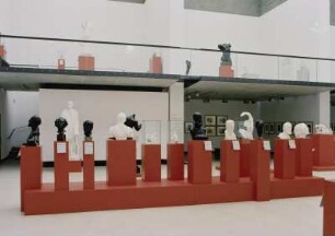 Raumaufnahme Ausstellungssaal. Blick über die Gruppe von Büsten und Porträtköpfen zur Empore