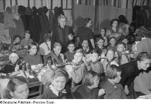 Kinder und Eltern an einer gedeckten und geschmückten Tafel bei der Weihnachtsfeier des Verlags Volk und Wissen