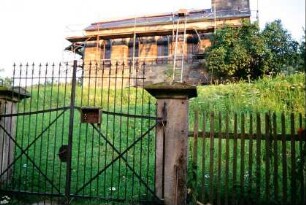 Eingang Kirchhof mit schmiedeeisernem Tor zwischen Sandsteinsäulen; Kirche eingerüstet