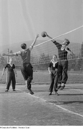 Zwei springende Volleyballspieler am Netz auf dem Spielfeld der Sportschule