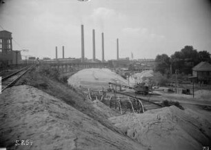 Industrie-Kraftwerk. Aufschüttung des neuen Bahndammes der Grubenbahn für die Kohlezufuhr, daneben aufgeständerte alte Trasse. Blick auf Werkanlagen mit Schornsteinen : Lauta (Niederlausitz). Industrie-Kraftwerk. Aufschüttung des neuen Bahndammes der Grubenbahn für die Kohlezufuhr, daneben aufgeständerte alte Trasse. Blick auf Werkanlagen mit Schornsteinen