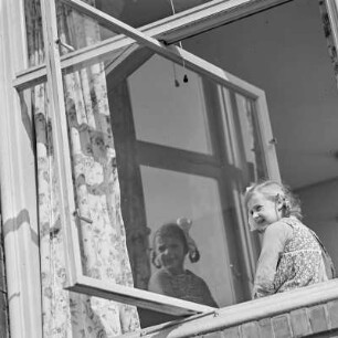 Mädchen mit Zöpfen und Schleifen schaut aus dem Fenster