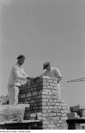 Zwei Arbeiter beim Errichten einer Mauer