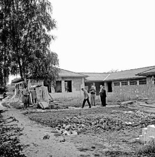 Sporteinrichtungen: Sportanlage am Kortenkamp: Sportlerheim: Sportverein (SV) Großhansdorf von 1942 e. V.: Rohbau: davor Personengruppe bei der Besichtigung: vorn Ziegelhaufen: links Baum: daran Stapel mit Bettern