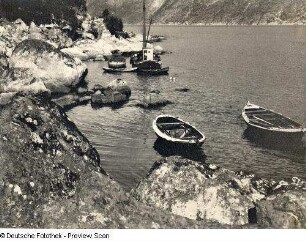 Fischerboot und Ruderboote an einer felsigen Küste. Ansicht vom Ufer