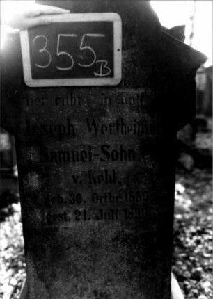 Grabstein 355 (Index: 100111911) Material: Sandstein, weiße Marmorplatte Zustand: leicht verwittert Maße HxBxT: 145x61x30 cm Beschreibung: ädikulaartige Stele mit Säulen, profilierter Sockel, schräg eingezogener Rundbogenabschluß mit Eckakroteren, Schriftplatte Symbolik: segnende Hände, Ranken, Rundbogenfries: Grabstein 355B