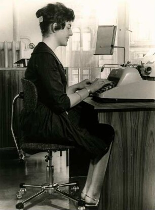 Büroarbeit. Eine Frau schreibt in einem Sekretariat Schreibmaschine. Der Arbeitsplatz ist korrekt eingerichtet