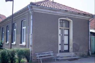altes Schulgebäude; davor Mast mit Lautsprecher (Dorffunk?)