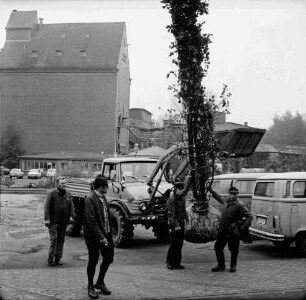 Pferdemarkt: Baumpflanzaktion: Kleintransporter mit Bagger: daran Baum mit Wurzelballen: rechts und links daneben Arbeiter: vorn links Mann: rechts Kleinbusse: hinten Backsteinsilo der Weizenmühle ["Gloria-Mühle"] der Johannes Ströh Mühlenwerke und weitere Gebäude