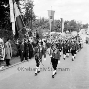 Schützenfest: Veranstalter Schützenverein Reinfeld und Umgebung von 1954 e.V.: Umzug: Tiroler Schützen der Schützenkompanie Wilten (bei Innsbruck) marschieren mit Fahnen: dahinter Pferdekutsche: an den Straßenrändern Zuschauer, Fahnenschmuck: hinten Festplatz an der Ahrensböker Straße, parkende Autos, 9. September 1962