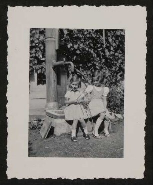 Zwei Mädchen (Christiane und Veronica?) sitzen am Brunnen im Hof in Rodaun