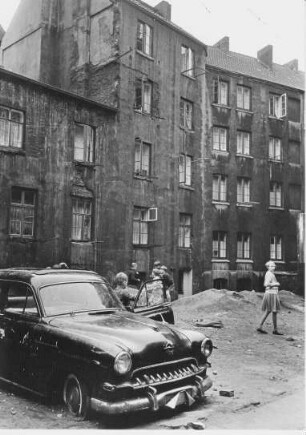 Hamburg-St. Pauli. Hinterhof in der Talstraße. Kinder spielen mit einem Autowrack