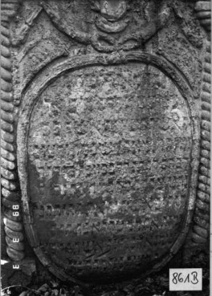 Grabstein 861 (Index: 99751235) Material: Sandstein Zustand: verwittert mit großem Textverlust Maße HxBxT: 138x79x13 cm Beschreibung: ädikulaart. St. m. gedrehten Halbsäulen, Volutenabschluß m. Mittelakroter, Symbolik: Levitenkanne mit Schale, Ranken, Girlande, Bänder: Grabstein 861B