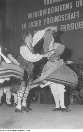 Tanzende Paare in Tracht auf der Bühne bei einer Veranstaltung zum Gedenken an die Völkerschlacht, im Hintergrund ein Orchester