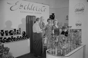 Mehrere Personen am Stand von Eschler & Co. Glasraffinerie Meiningen auf der Leipziger Herbstmesse 1955
