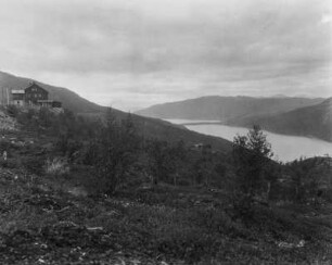 Landschaft : Blick über die Landschaft eines Gletschers auf den Fjord. Am linken Bildrand steht ein Haus.