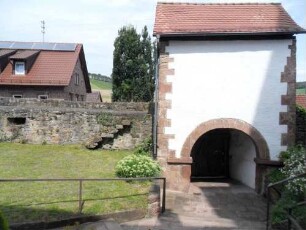 Kirchhof im Norden-Torhaus von Süden (Romanisch mit Torbogen auf Kämpfern) mit Durchgang und im Westen anschließender Kirchhofmauer mit Schießscharten sowie Steinbrüstung und Treppe