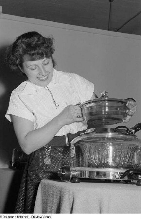 Eine Frau präsentiert auf der Herbstmesse 1953 "Die kleine Küche " des VEB (K) Elektrogerätebau Leipzig