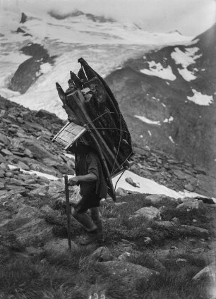Holzträger : Ein Mann trägt ein Rückentrage mit Leseholz einen Berg hinauf.