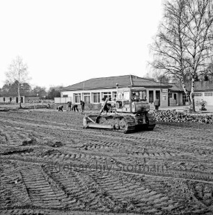 Sporteinrichtungen: Sportanlage am Kortenkamp: Ausbau: Hauptspielfeld: Aufbringen von Kies: in der Mitte Planierraupe: dahinter Arbeiter: hinten Sportlerheim: rechts Baum