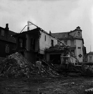 Firma Carl Hoffmann: Hindenburgstraße: Elektrohandel: Abriss des Firmengebäudes: Bauschutt mit Bretterhaufen: dazwischen Bagger: links Wohn- und Geschäftshaus: hinten rechts Wohn- und Geschäftshaus mit Drogerie Purnhagen