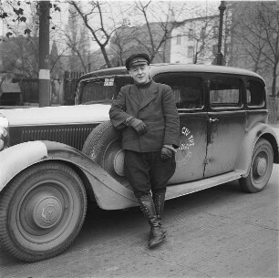 Halbmilitärisch gekleideter Fahrer an einem englisch beschrifteten Personenkraftwagen (Hilfsdienst für alliierte Streitkräfte)