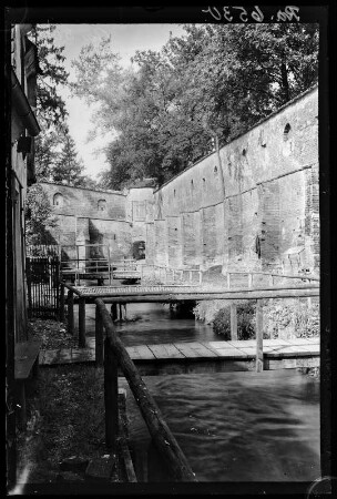 Unbekannter Ort. Stadtmauer mit Wassergraben und Stegen