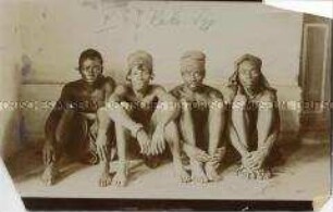 Gruppenbild vierer sitzender Männer der Bangandu vor neutralem Hintergrund