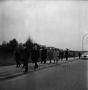 Stadtverordnete und Mitarbeiter der Stadtverwaltung: Flurbegehung durch Stadt, verlängerten Wendum, Ehmkenberg und Kneeden: Ehmkenberg: Gruppe auf Gehweg: dahinter Wohnblocks und Bäume: 26. Oktober 1968