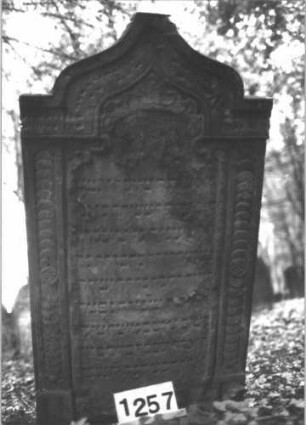 Grabstein 1257 (Index: 99900073) Material: Sandstein Zustand: stark verwittert Maße HxBxT: 125x69x13 cm Beschreibung: Stele mit Kielbogenabschluss, im Bogenfeld Akanthusornamente, seitlicher Rahmen mit Schuppenfries Symbolik: Akanthus, Schuppenfries: Grabstein 1257