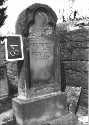 Grabstein 81 (Index: 100114072) Material: Sandstein Zustand: beschädigt, abgeblättert, gebrochen und repariert mit Textverlust Maße HxBxT: 140x48x20 cm Beschreibung: Stele, getreppter Sockel, Rundbogenabschluß, Schriftfeld mit Kleeblattbogenabschluß: Grabstein 81