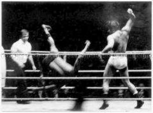 Zwei Boxer und ein Schiedsrichter im Ring, ein Boxer stürzt