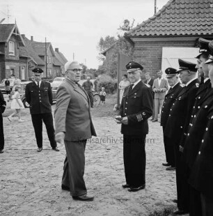 Freiwillige Feuerwehr: Übergabe eines neuen Löschfahrzeugs: Schlüsselübergabe an Wehrführer Ernst Gerken durch Bürgermeister Karl Timm: rechts Feuerwehrmänner: hinten links Kreisbrandmeister Hinrich Harms: dahinter Zuschauer: im Hintergrund links Bauernhaus, rechts Feuerwehrgerätehaus