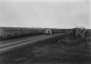 Brasilianische Landschaft : Ein Auto steht auf einer Straße in einer flachen brasilianischen Landschaft. An den Straßenrängern stehen Zäune.